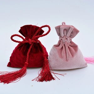 Detailed view of red and pink velvet drawstring bags with elegant tassels for gifts
