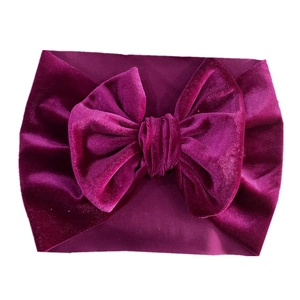 Detail of purple velvet baby headband featuring a large soft bow on a white background