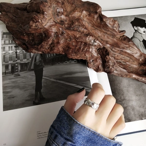 Detail of a 925 sterling silver woven ring with irregular fold texture on model's finger