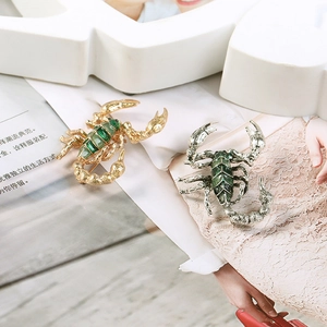 Detailed view of scorpion brooch in gold and antique silver with green enamel oil drips