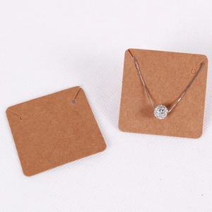 Close-up of blank kraft paper jewelry display card with silver spherical pendant necklace