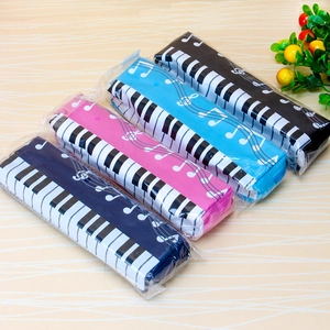 Flat lay of piano keyboard pattern pencil pouches in four colors on wooden surface