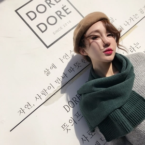 Detailed texture of thick dark green knit scarf and khaki wool beret in soft winter light
