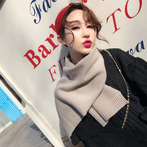 Detail shot of beige thick knitted short scarf worn by a model in outdoor lighting