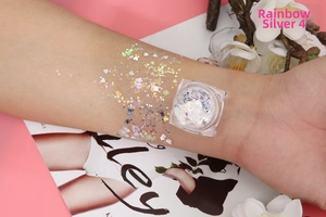 Macro shot of iridescent silver cosmetic glitter gel with star and heart shapes on skin