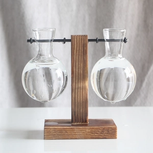 Close-up of two spherical glass vases suspended on a dark wooden frame for hydroponic plants