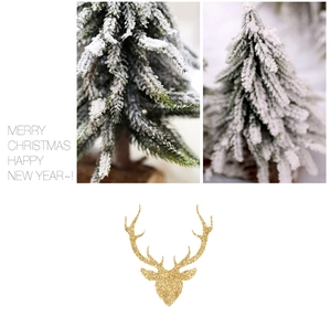 Close-up of artificial snow-covered Christmas trees and golden glitter reindeer head decor