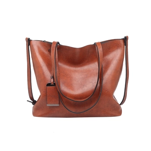 Detail view of large brown PU leather tote bag with long straps on white background