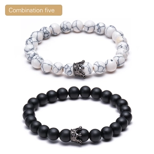 Close-up of white marble and black matte lava stone bracelets with micro-pave crown charms