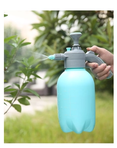 Macro shot of 2L garden pressure sprayer nozzle releasing a fine mist over green plants