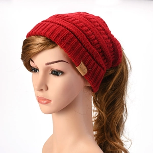 Detail of red cable knit ponytail beanie with CC leather label on ribbed cuff