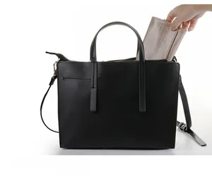 Detail showing internal storage space of black lychee leather tote with a small gold pouch