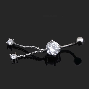 Close-up of dangling zircon belly ring with crystals and chains on reflective surface
