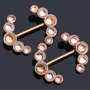 Macro detail of rose gold nipple piercing shields with champagne cubic zirconia stones