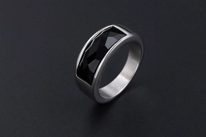 Macro detail of men's stainless steel ring with faceted black stone and silver finish