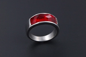 Macro shot of wide silver stainless steel ring with faceted red gemstone inlay