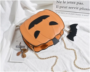 Detail of pumpkin crossbody bag with black face patch and gold metal chain strap