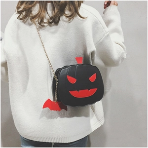 Detail of Halloween pumpkin crossbody bag with red bat charm and gold chain strap
