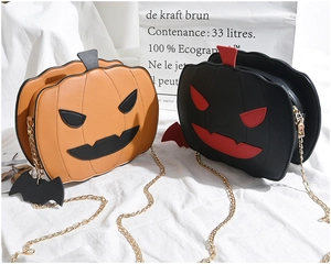 Detail of pumpkin crossbody bag with stitched demon face and black bat pendant accessory