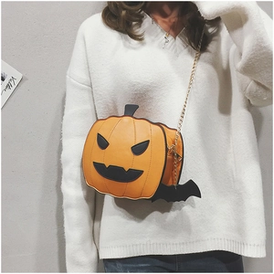 Detail of pumpkin crossbody bag featuring black bat wings and gold chain strap