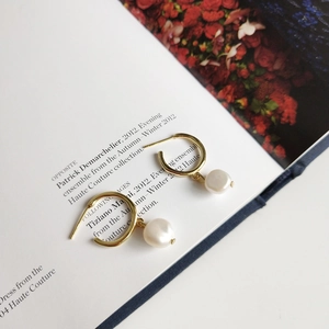 Detail of 925 silver hoop earrings with irregular freshwater pearls on a magazine