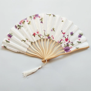 Flat lay of an open folding fan featuring delicate purple floral patterns and white tassel