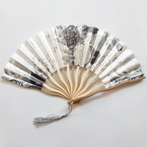 Detailed view of a Japanese bamboo hand fan with monochrome floral ink painting and grey tassel