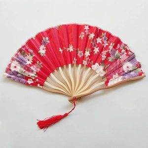 Detailed view of a red Japanese folding fan with cherry blossom patterns and a red tassel