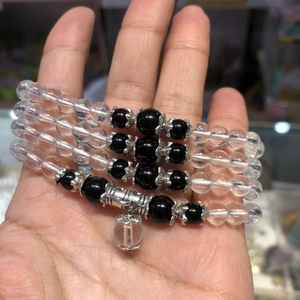 Macro shot of layered glass bead bracelets with silver charms held in palm