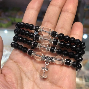 Detail of four crystal beaded bracelets with silver accents held in hand for close-up