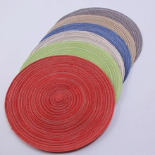 Stack of six colorful round braided placemats in red, green, blue, beige and brown