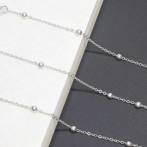 Detailed view of silver eyeglass chain with metallic round beads on a textured background