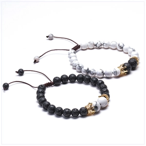 Detail of couple bracelets with lava stone, turquoise and golden crown adjustable charms