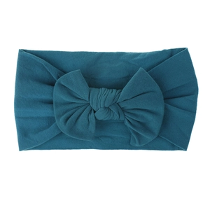 Dettaglio di una fascia per neonati in nylon morbido con un grande fiocco color blu pavone
