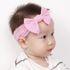 Vista dettagliata di una fascia in nylon rosa morbido con fiocco indossata da un neonato