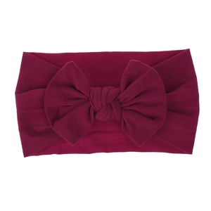 Dettaglio di una fascia per neonati in morbido nylon con grande fiocco rosso scuro elastico