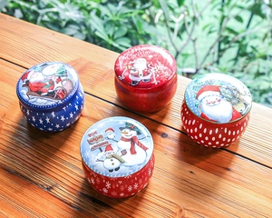 Close-up of four colorful Christmas tin storage boxes on a natural wood surface