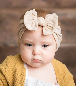 Close-up of a soft nylon beige bow headband worn by a baby girl for infant fashion