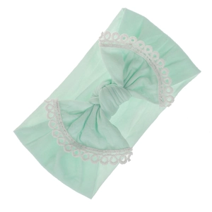 Detail of mint green baby headband with soft lace edges and a large fabric bow
