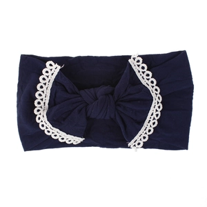Detailed view of a soft navy blue nylon baby headband with an elegant lace-trimmed bow