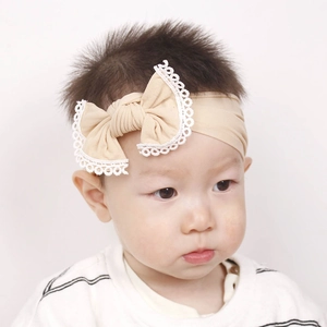 Detail of baby headband with soft lace-edged bow in beige ribbed stretch fabric