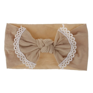 Detail showing soft nylon baby headband with lace-edged bow in light brown color