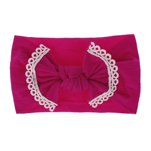 Close-up of rose red baby headband featuring soft knit fabric and white lace trim bow