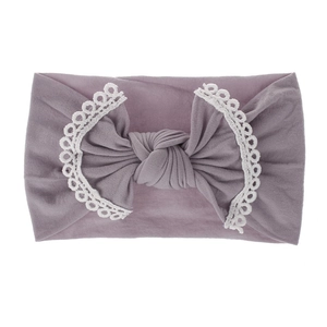 Detail of dusty purple baby headband featuring a large bow with white lace trim edges