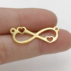 Macro detail of golden infinite heart connector charm for jewelry making on finger
