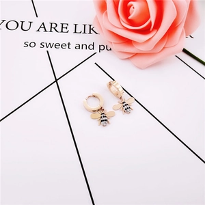 Boucles d'oreilles abeille or rose avec cristaux pavés sur fond minimaliste