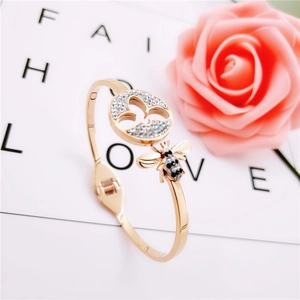Détail d'un jonc en or rose avec une abeille pavée et un pendentif rond serti de cristaux
