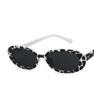 Cow pattern oval sunglasses with stylish white temples and dark grey tinted lenses