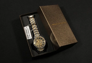 Gros plan sur une montre mécanique squelette avec bracelet bicolore et coffret cadeau