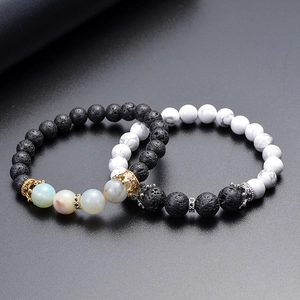 Macro detail of natural lava stone and white turquoise bracelets with crown charms